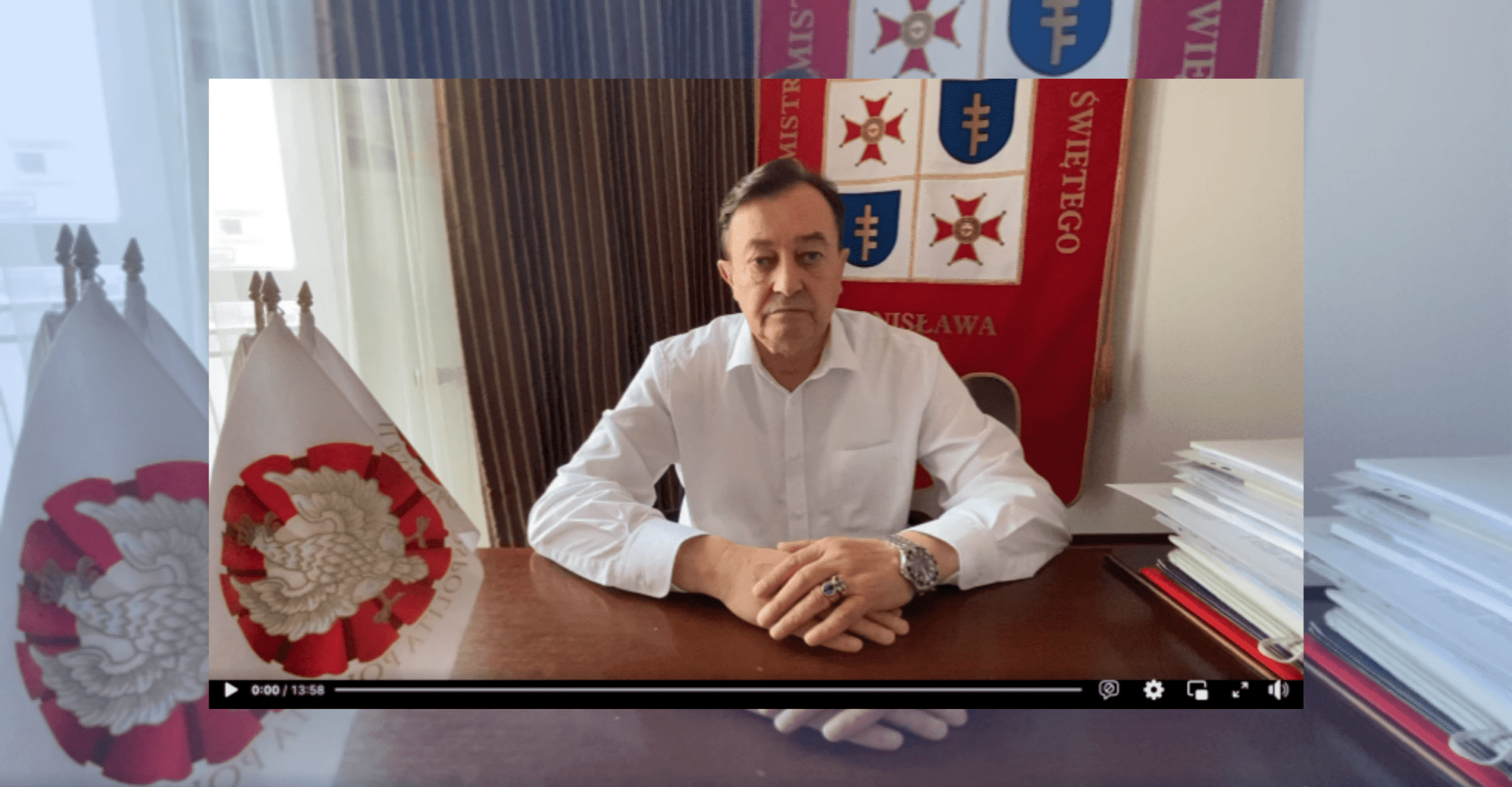 Screenshot filmiku Jana Zbigniewa Potockiego, samozwańczego "prezydenta Polski". Ubrany jest w białą koszulę. Siedzi przy stole.