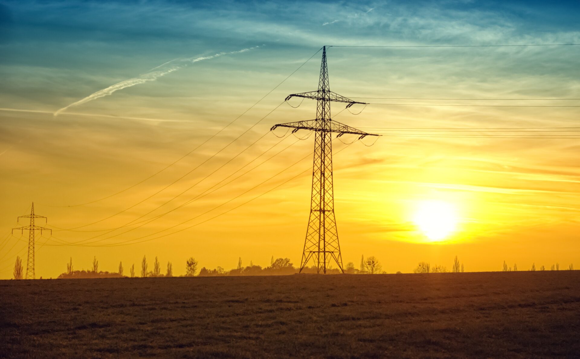 napowietrzna linia elektroenergetyczna na tle zachodzącego słońca