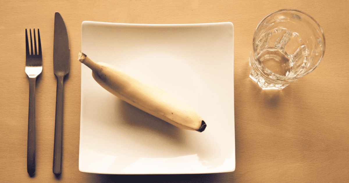 sztućce, banan i szklanka wody na stole