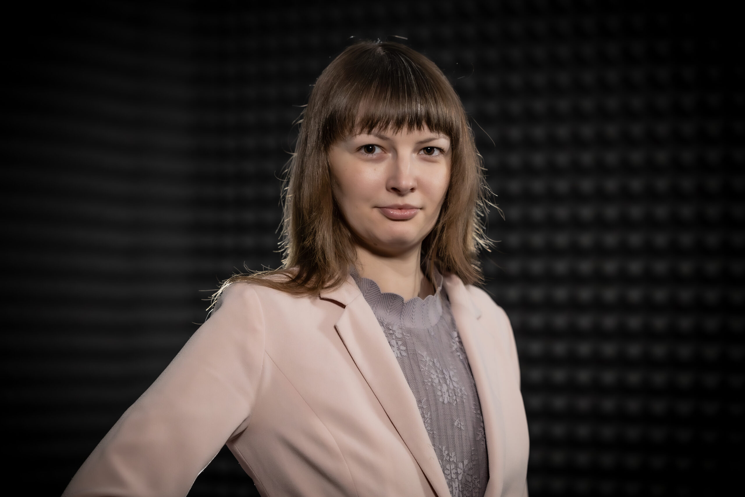 Monika Lewkowicz od klatki piersiowej w górę z ręką na boku na ciemnym tle