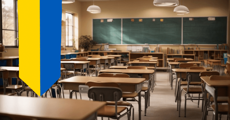 Szkolna klasa z długą tablicą kredową i ławkami, po lewej stronie nałożona grafika z flagą Ukrainy.