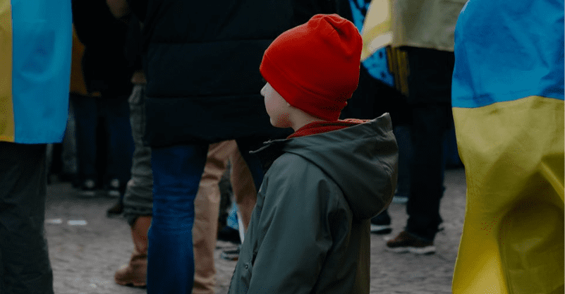 w tle flagi Ukrainy i chłopiec stojący w tłumie