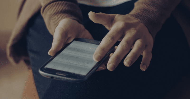 w tle dłonie trzymające telefon