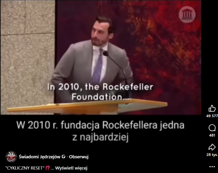 Zrzut ekranu z platformy Facebook, gdzie pojawia się mężczyzna ubrany w garnitur, który przemawia do mikrofonu.