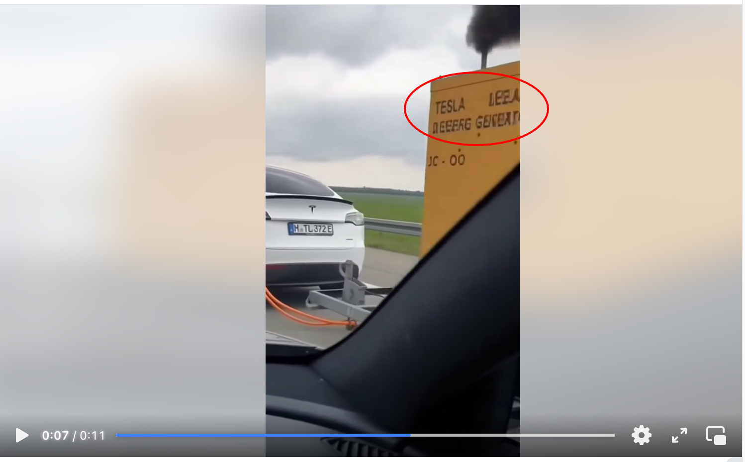 Zrzut ekranu posta na Facebooku. W kadrze filmu znajduje się przyczepa z żółtym generatorem doczepiona do białej Tesli. Z komina wydobywają się spaliny.