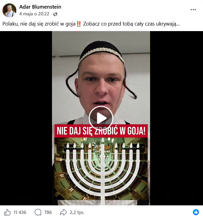 Zrzut ekranu wpisu z Facebooka. Na górze podpis i elementy interfejsu platformy, na dole klatka z nagrania przedstawiająca mężczyznę z pejsami i jarmułką, oraz zdjęcie sali sejmowej z nałożoną grafiką menory.