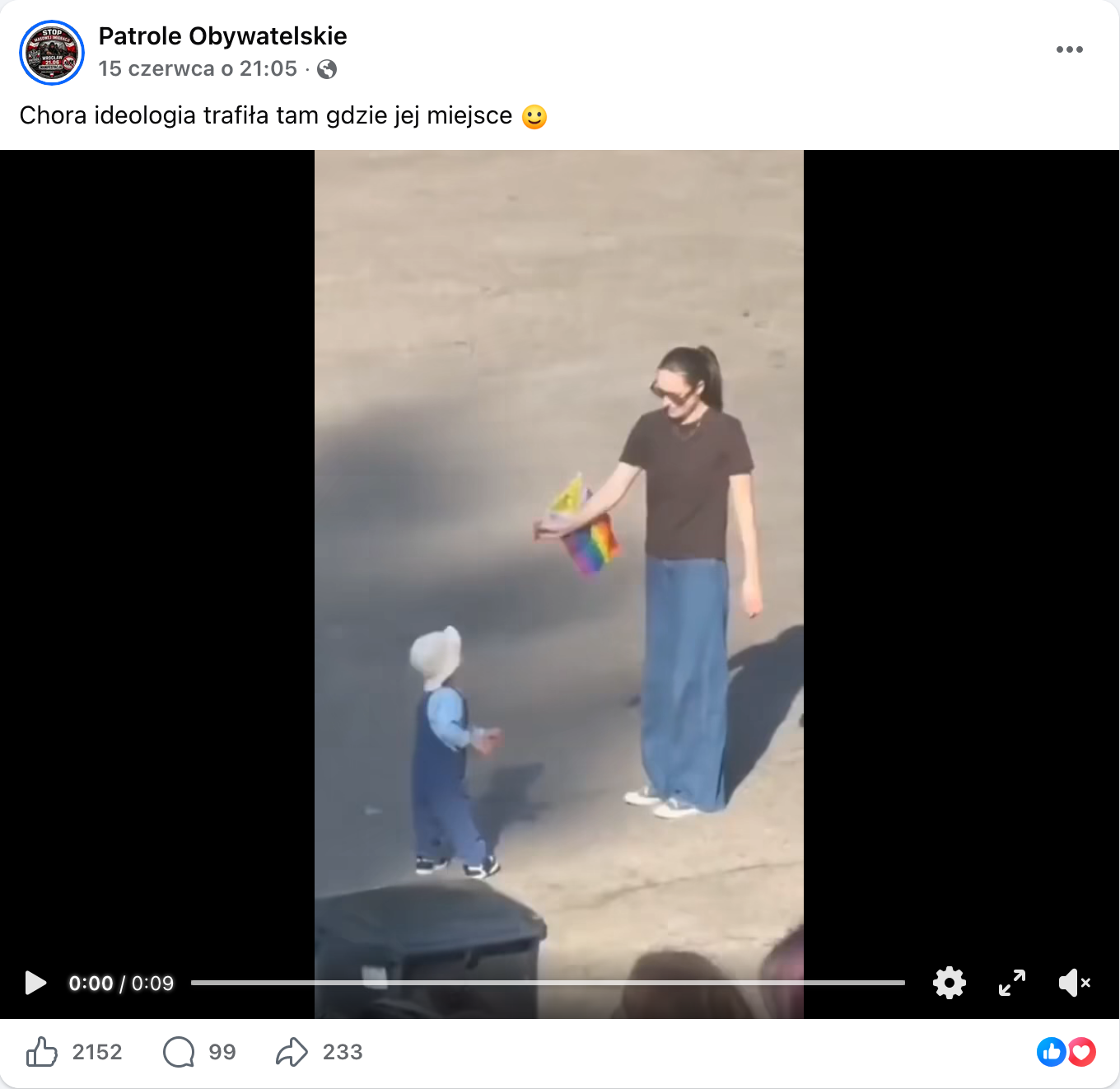 Zrzut ekranu przedstawiający nagranie opublikowane na Facebooku. W kadrze widać kobietę, która podaje tęczową flagę dziecku.